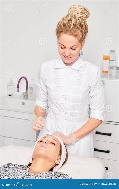 Beautician Applying Cosmetic Cream Mask On Female Face For Rejuvenation