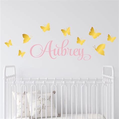 A White Crib With Pink And Yellow Butterflies On The Wall Next To A