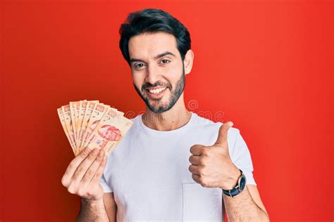 Young Hispanic Man Holding Mexican Pesos Smiling Happy And Positive
