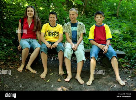 Teenagers With Bare Feet Sitting On A Bench In A Forest Stock Photo Alamy