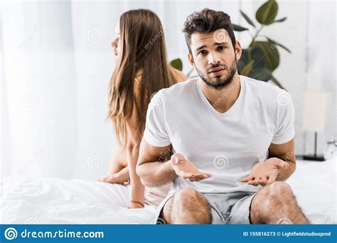 Young Frustrated Man Having Sexual Problems While Sitting On Bed Next