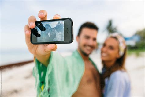 Young Happy Couple Of Man And Woman Taking A Selfie With Their Phone In A Tropical Beach At
