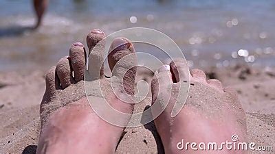 Tanned Red Bare Female Feet In Sand Lies On A Sandy Beach On Coast Of