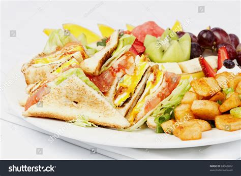 Breakfast Club Sandwich And Assorted Fruits On White Plate Stock Photo