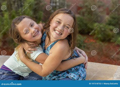 Sisters Embrace Each Other In A Warm Hug While Smiling At The Camera Stock Image Image Of