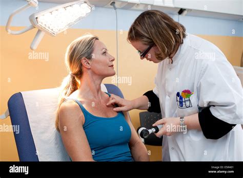 Dermatologist Examining Skin Of Female Patient With Dermatoscope