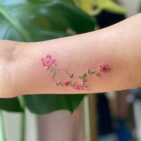 a woman s arm with pink flowers on it and the word love written in cursive writing