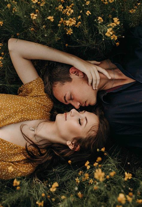 A Girl And A Boy Laying In A Field With Their Heads Next To Each Other Nearly Kissing Engagement