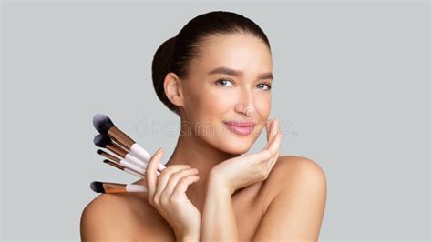 Smiling Caucasian Young Woman Holding Her Makeup Brushes Stock Image