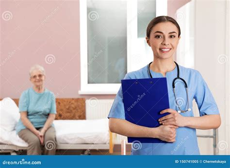 Portrait Of Nurse With Clipboard In Senior Patient`s Hospital Stock