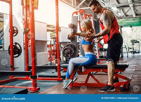 Sporty Girl Doing Weight Exercises With Assistance Of Her Personal Trainer At Gym Stock Image