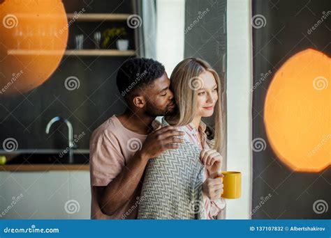 Loving Black African Young Man Hugs His Caucasian Wife Stock Photo