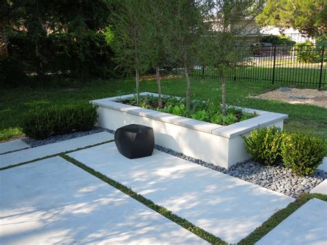 An Outdoor Garden Area With White Concrete And Green Plants In The