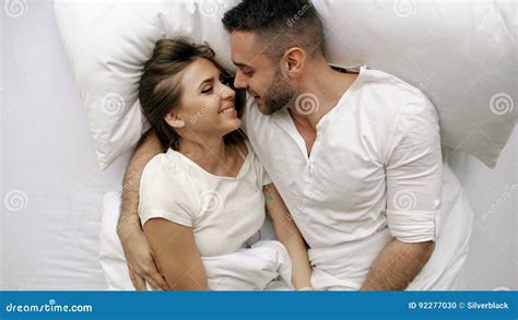 Young Beautiful And Loving Couple Talk And Hug Into Bed While Waking Up In The Morning Top View