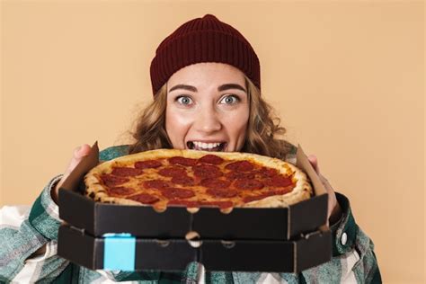 premium photo photo of pretty excited woman in knit hat eating pizza isolated on beige