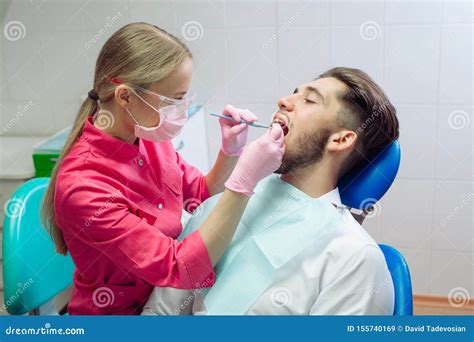 Professional Teeth Cleaning Dentist Cleans The Teeth Of A Male Patient