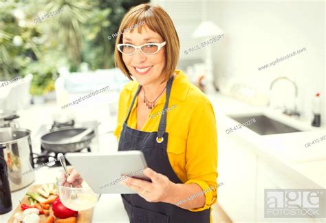 Portrait Smiling Mature Woman With Digital Tablet Cooking In Kitchen