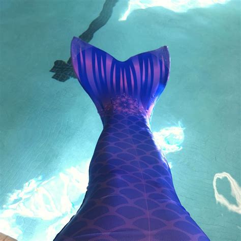 A Womans Purple Fish Tail Swimsuit In A Pool With Clear Blue Water