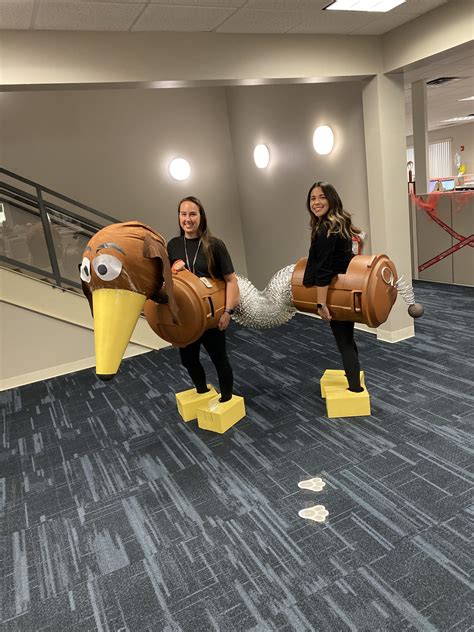 two women in costumes are posing for a photo while holding giant fake birds on their legs