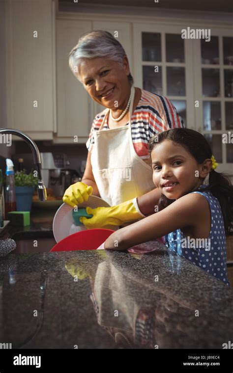 Portrait Of Grandmother And Granddaughter Washing Utensil In Kitchen