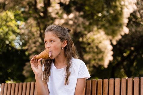 와플 컵에 아이스크림 콘을 먹는 재미있는 어린 소녀 아이스크림 스탠드 및 상점을 위한 창의적인 광고 프리미엄 사진