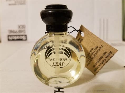 A Bottle Of Perfume Sitting On Top Of A White Table Next To A Tag That
