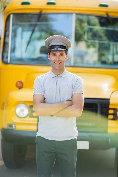 Smiling Bus Driver Standing With Hands In Pocket In Front Of Bus Stock