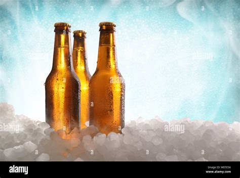 Three Full Beer Bottles On Crushed Ice And Blue Gradient Background