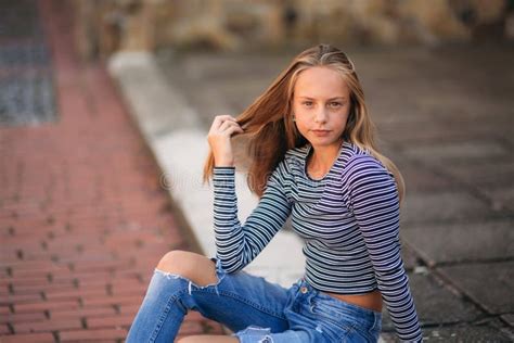 Young Teenage Poses For Photo Blonde Girl In Jeans And Blouse Play