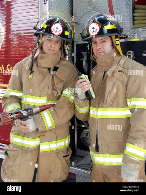 Male And Female Firefighters Standing In Front Of Fire Truck With Radio