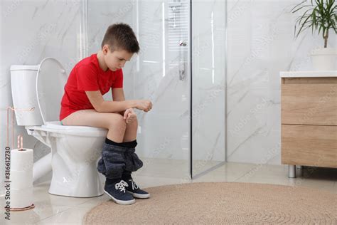 Boy Suffering From Hemorrhoid On Toilet Bowl In Rest Room Stock Photo