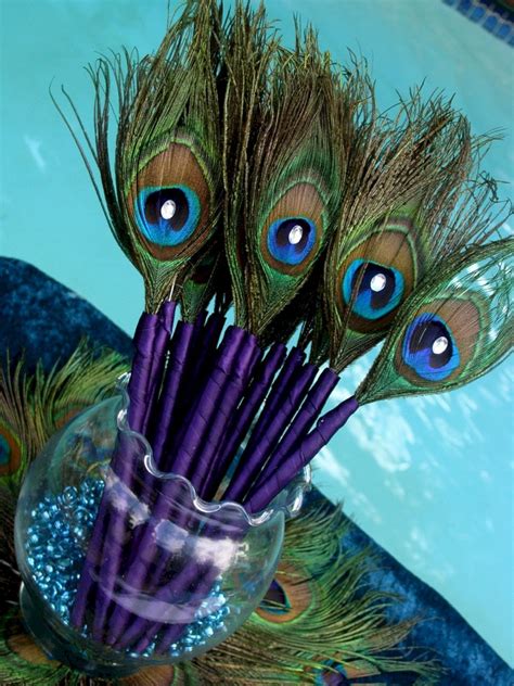 A Vase Filled With Purple And Green Feathers On Top Of A Table Next To