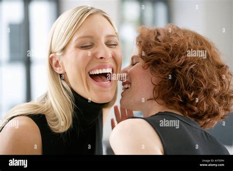 Two laughing young women whispering Stock Photo - Alamy