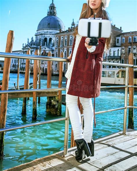 Woman On Embankment In Venice Taking Selfie Using Selfie Stick Stock