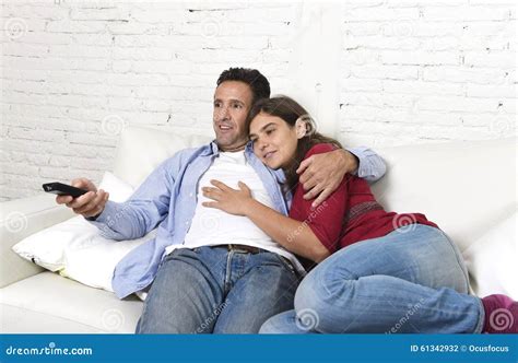 Couple In Love Cuddling On Home Couch Relaxing Watching Movie On