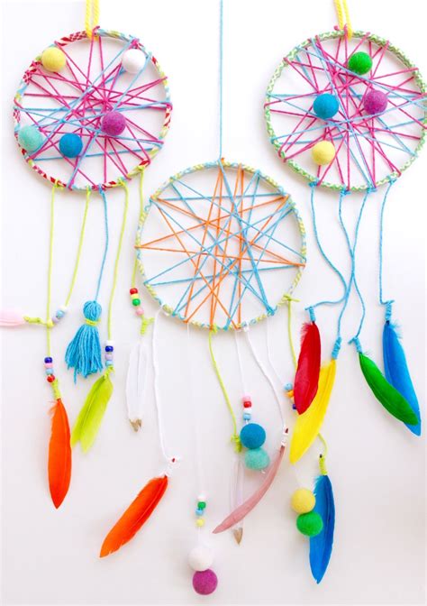 Two Colorful Dream Catchers Hanging From Strings On A White Wall With