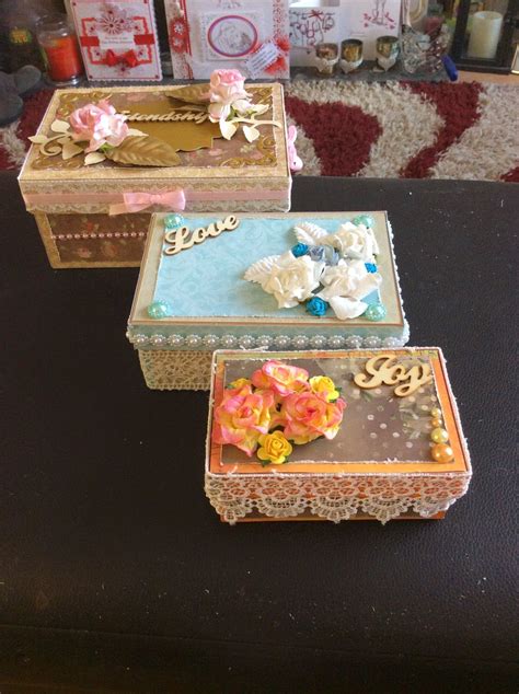 Three Decorative Boxes Sitting On Top Of A Table
