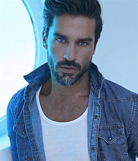A Man With A Goatee And Beard Wearing A Denim Jacket Looking At The Camera