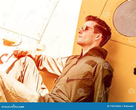 A Handsome Young Pilot Sitting On The Wing Of A Plane Stock Photo