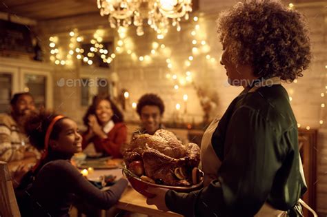 Happy Black Woman Bringing Thanksgiving Turkey To Dining Table During