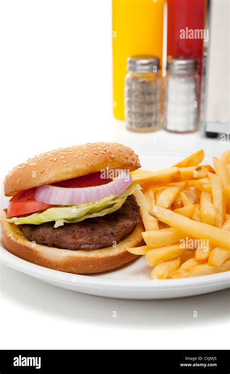 Hamburger And Fries On A Table With Salt Pepper Mustard Ketchup And