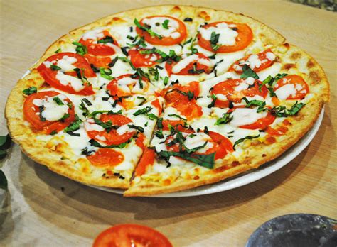 A light pizza with olive oil, garlic, fresh basil, fresh tomatoes, mozzarella and parmesan cheeses. Margherita Flatbread Pizza - Recipe Treasure