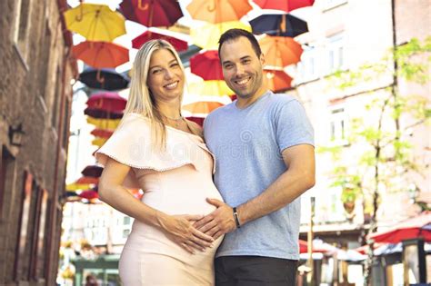 Pregnant Woman With Boyfriend On City Street With Umbrella On The