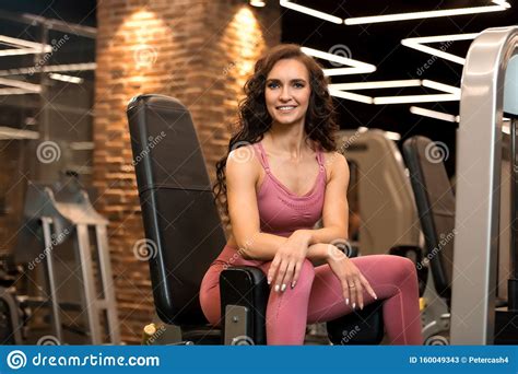 Fitness Brunette Woman Is Sitting In Training Apparatus For Legs In The