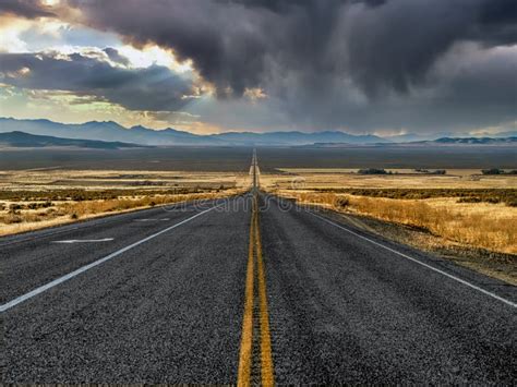 Straight Road Leading Through A Stormy Nevada Desert Landscape Stock
