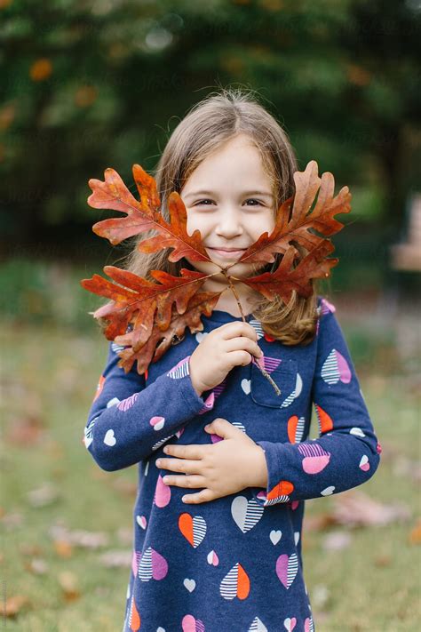 Cute Young Girl Holding Up A Branch With Leaves To Her Face By Stocksy Contributor Jakob