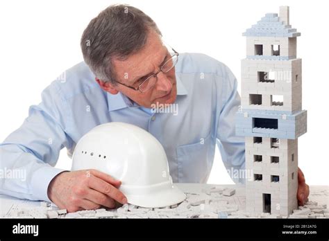 Mature Architect Examining A House Of Toy Blocks Stock Photo Alamy