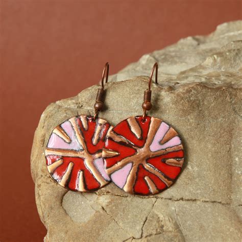 Two Red And Pink Heart Shaped Earrings Sitting On Top Of A Rocky