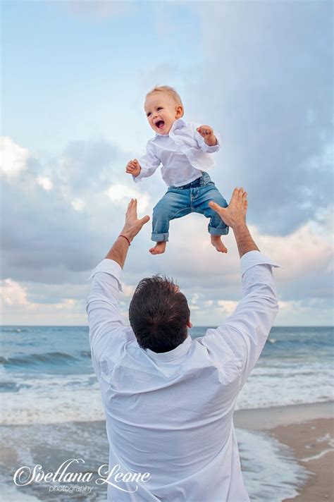 A Man Holding A Baby Up In The Air