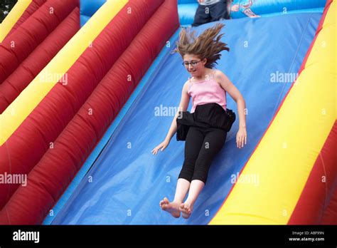 An 11 Year Old Girl With Trailing Hair Slides Fast Down A Slope On An Inflatable Slide In